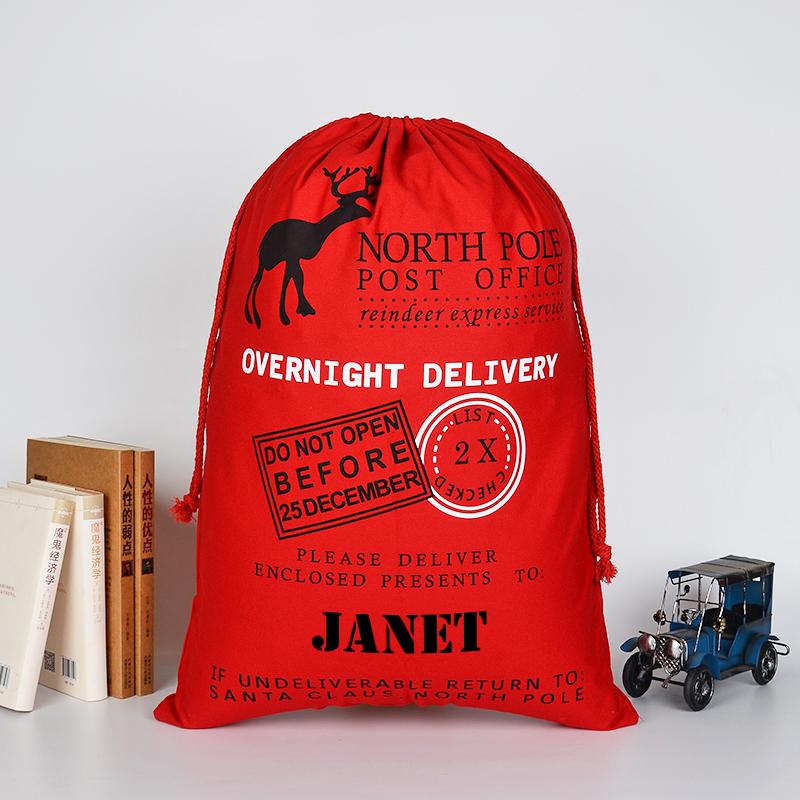 A personalised red Christmas sack with a vintage style postage design and a child's name printed at the bottom.
