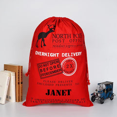 A personalised red Christmas sack with a vintage style postage design and a child's name printed at the bottom.