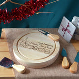 A personalised Christmas cheese board with an engraved design. The board is round with a pull out compartment for 4 cheese knives.