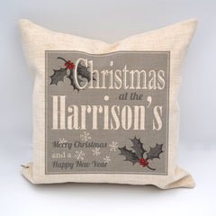 A personalised white, grey and red Christmas cushion with a text based design and holly leaf illustrations