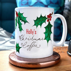 A personalised Christmas mug with the message "Holly's Christmas Coffee" and illustrations of holly leaves printed onto it.