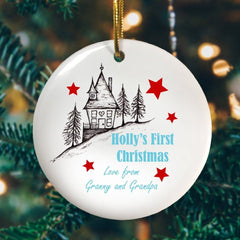 A round ceramic Christmas decoration with an illustration of a house and the words "Holly's First Christmas love Granny and Grandpa"
