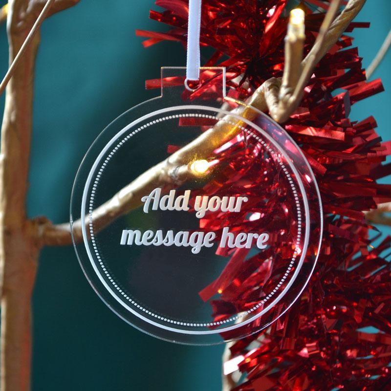 A personalised round clear acrylic Christmas decoration with an engraved message in white.
