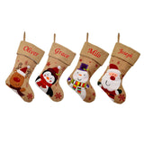 4 personalised hessian Christmas stockings, one with a penguin, one with Santa, one with a snowman and one with a reindeer. All the stockings have a christian name embroidered on the top of the stocking in red lettering. 