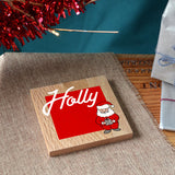 A personalised Christmas coaster in solid oak with a name and Santa printed on the front.