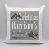 A personalised white, grey and red Christmas cushion with a text based design and holly leaf illustrations