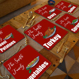 A dining table with personalised Christmas placemats on. The placemats are red with white text and illustrations of Christmas food 