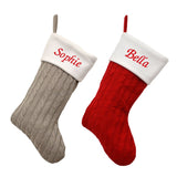 2 personalised knitted Christmas stockings, one in a pale grey knitted material and one in a red knitted material. Both stockings have a white top and are embroidered with a name in red. 