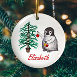 A personalised circular Christmas decoration with a penguin and Christmas tree image printed onto it