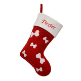 A personalised pet Christmas stocking with white bones on a red background, the stocking is embroidered with the name "Dexter" on the white top of the stocking.