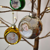 A personalised silver Christmas bauble with a photo of a baby printed on it.