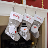 A close up of 3 personalised Christmas stockings, one with a snowman, one with a reindeer and one with santa