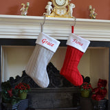 2 personalised knitted christmas stockings hanging on a fire place 